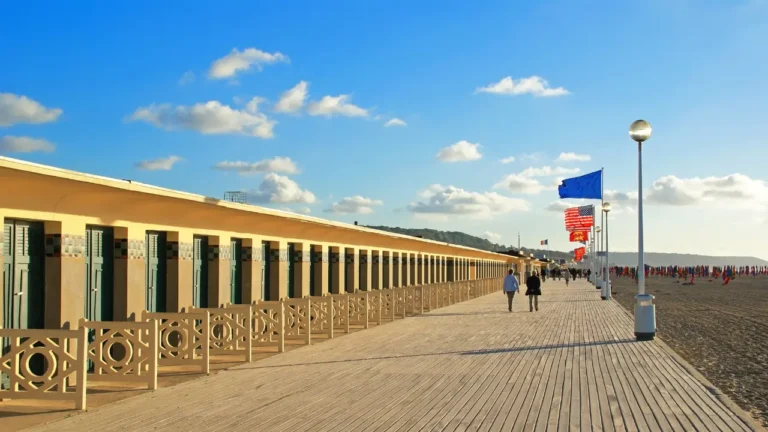 Planches de Deauville le long de la plage avec cabines et drapeaux, promenade emblématique et activités touristiques à découvrir en 2026.